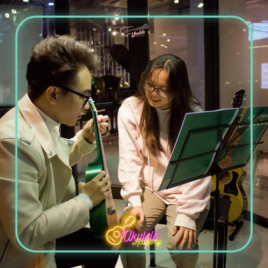 Giáo viên thị phạm ukulele bên học viên và giá nhạc