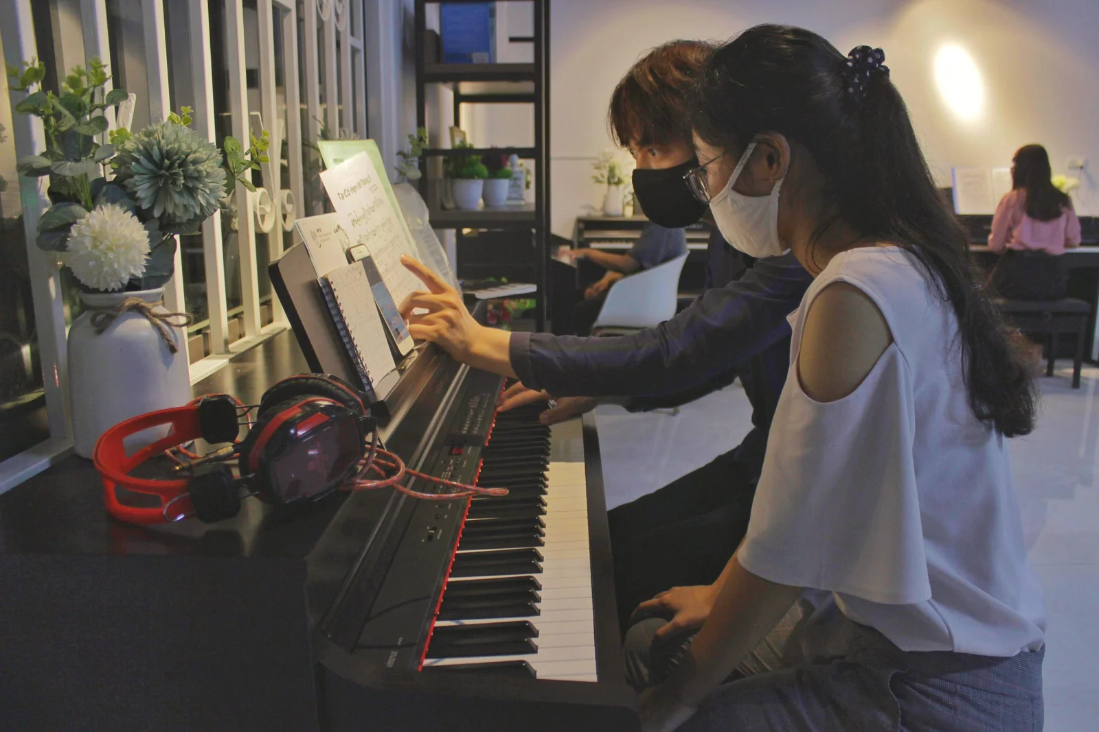 Hai người cùng luyện tập Piano trong phòng học